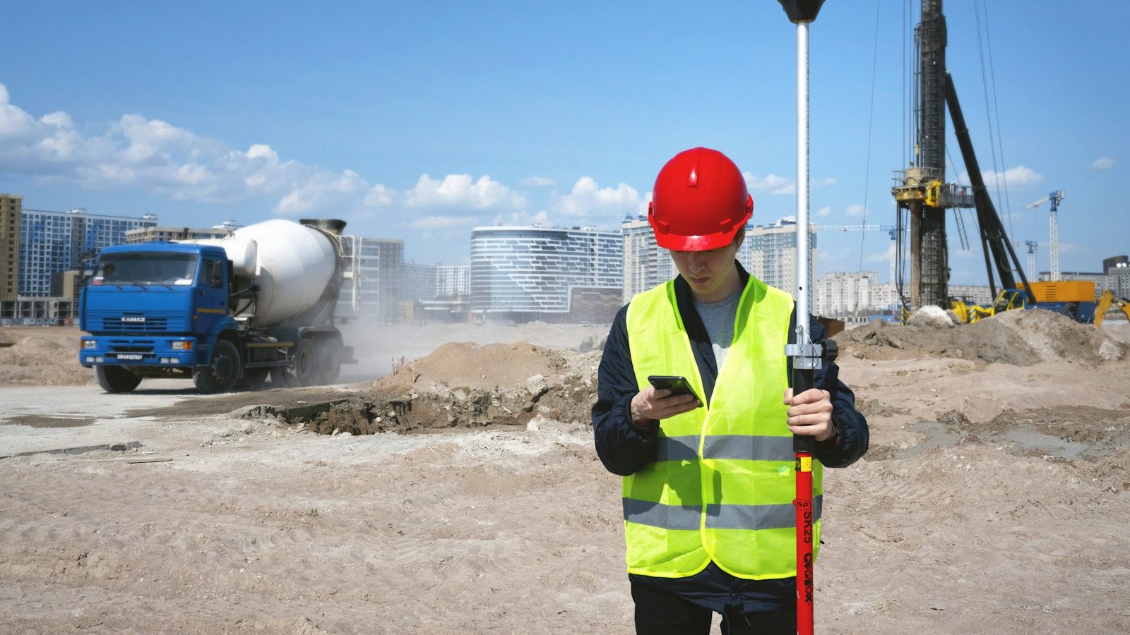 Vermessungstechniker mit Warnweste und Messstab auf einer Baustelle