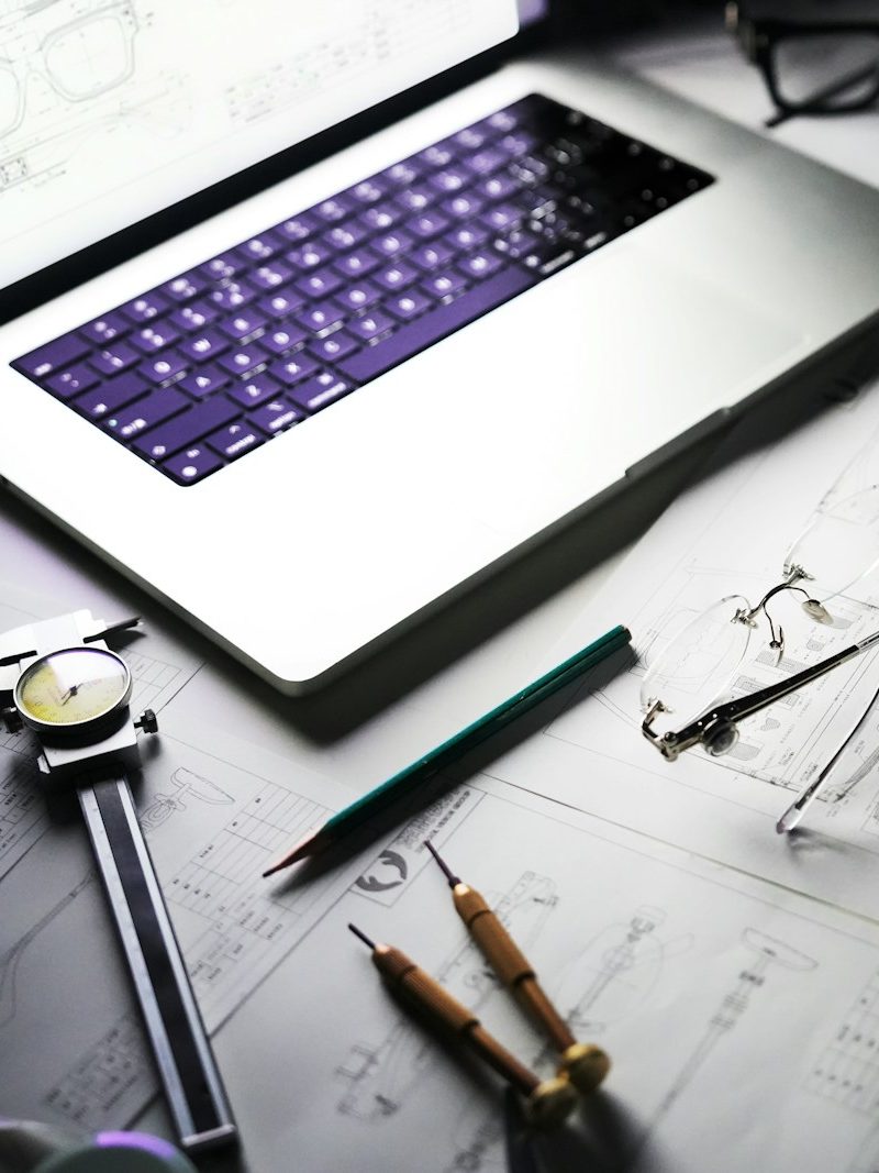 Technische Zeichnung mit Zirkel, Stift und Laptop auf einem Schreibtisch